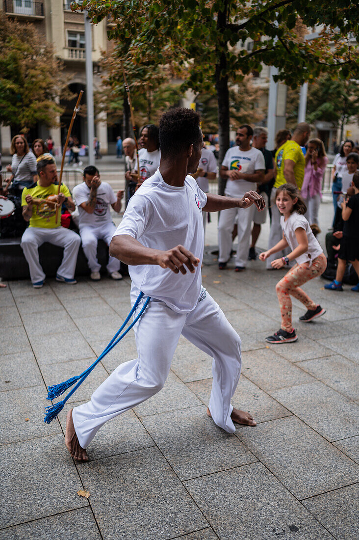 Mitglieder der Mestre Branco Capoeira Escola demonstrieren auf der Straße während der Fiestas de El Pilar in Zaragoza, Aragonien, Spanien