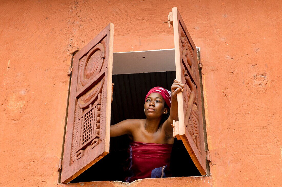 Benin, Abomey, woman opening window of Abomey museum