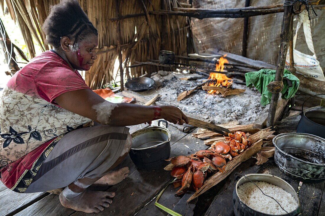 Indonesien, Papua, Bezirk Asmat, Dorf Per, Pfahlzeremonie, Frau bereitet Krabben zu