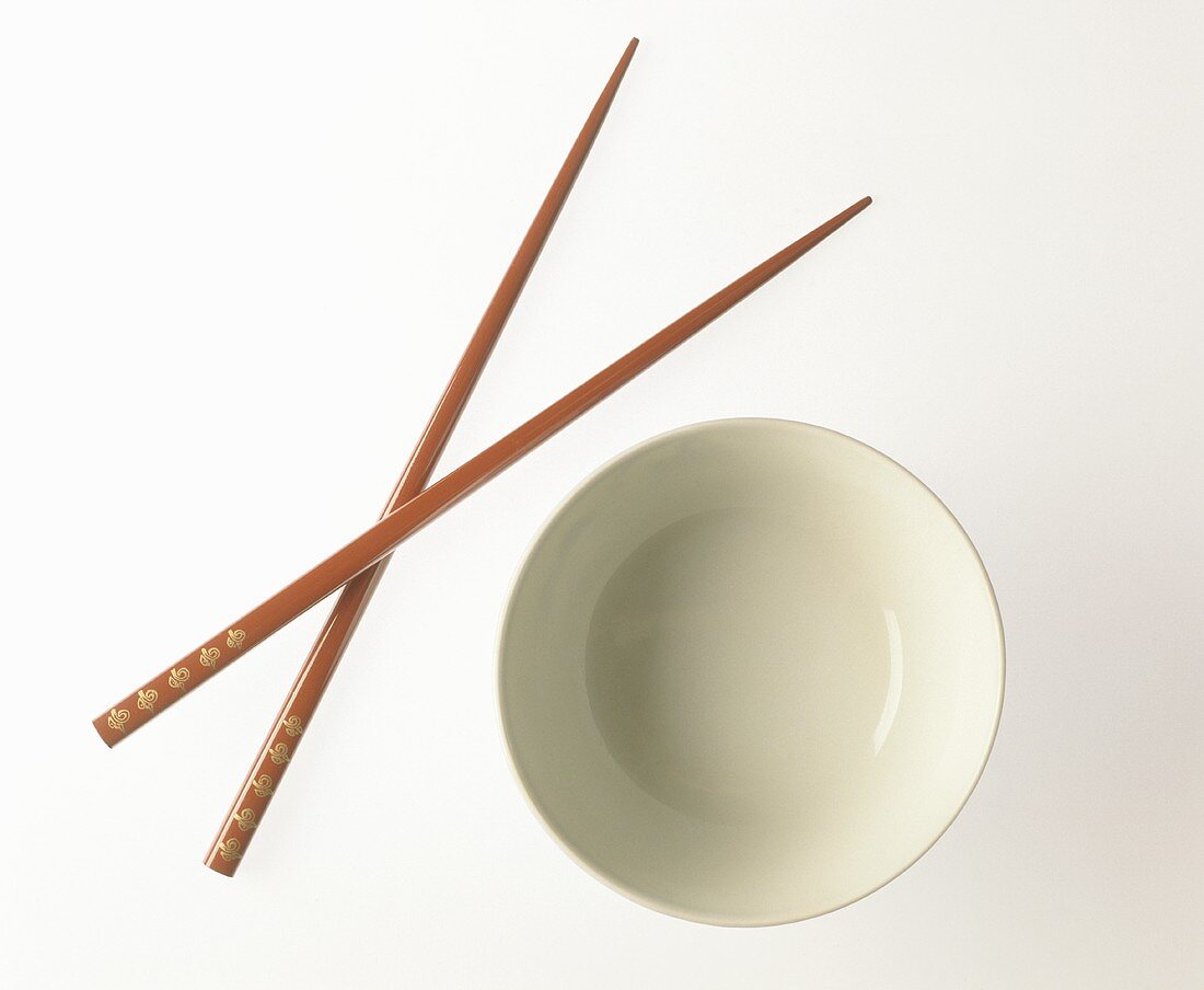A bowl of rice and two red chopsticks