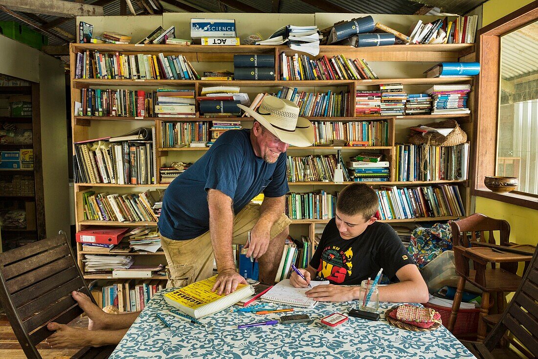 Papua New Guinea, East Sepik Province, Sepik River Region, Angoram District, Samban Village, US Missionary Jesse Pryor checking the home work of his son