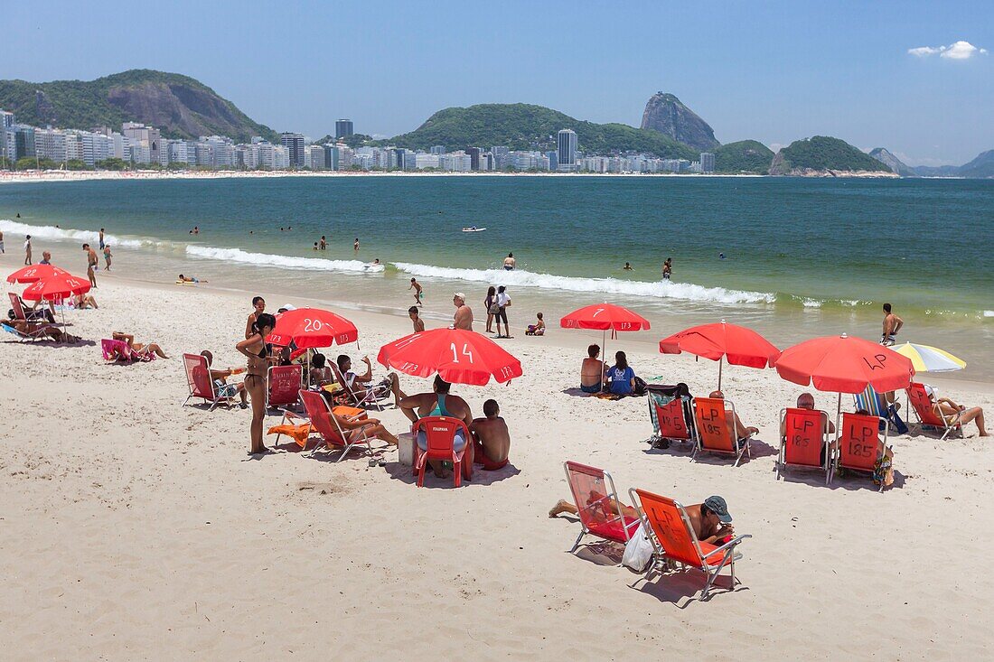 Brazil, state of Rio de Janeiro, city of Rio de Janeiro, Copacabana beach, Carioca landscapes between mountain and sea classified UNESCO World Heritage, sunbed seats and red umbrellas