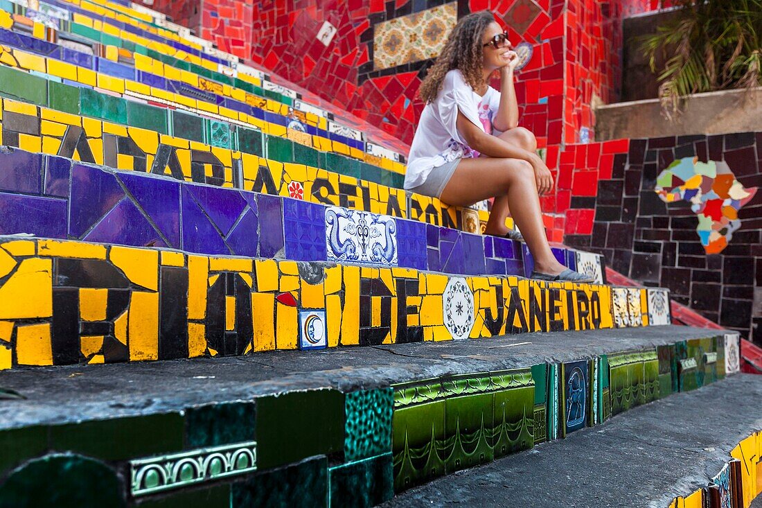 Brasilien,Bundesstaat Rio de Janeiro,Stadt Rio de Janeiro,Carioca-Landschaften zwischen Berg und Meer,UNESCO-Weltkulturerbe,Stadtteil Santa Teresa,Treppe aus Keramikfliesen des Künstlers Jorge Selarón,junge Frau auf Treppe sitzend