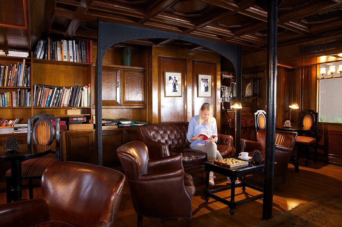 Egypt, Upper Egypt, Nile Valley, tourist sitting in a chesterfield sofa in the British style lounge of Steam Ship Sudan, the last steamboat on the Nile