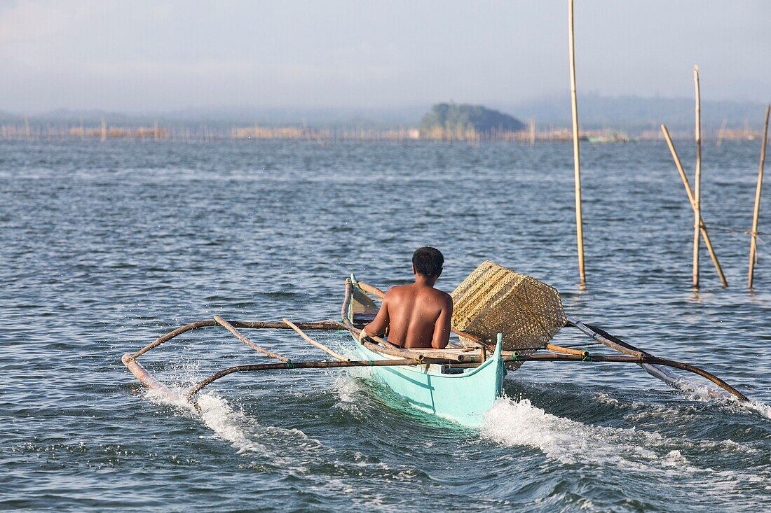 Philippines, Palawan, Malampaya Sound Protected Landscape and Seascape, fisherman sailling on his boat with traps