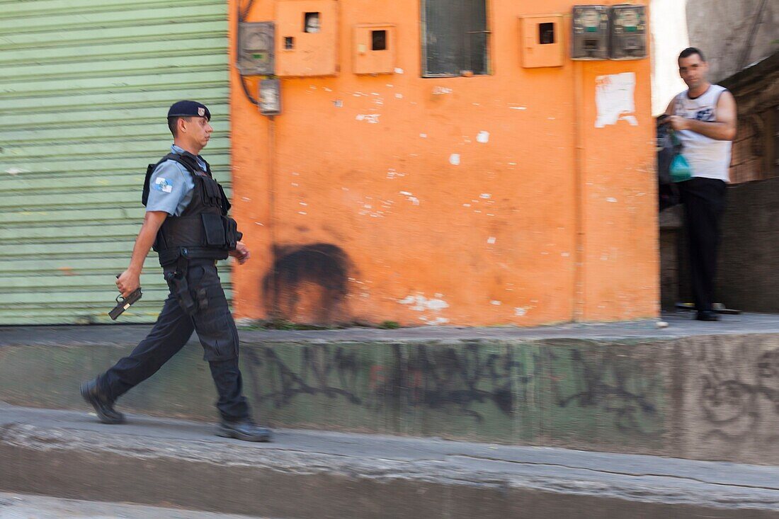 Brazil, state of Rio de Janeiro, city of Rio de Janeiro, favela Rocinha, Carioca landscapes between the mountain and the sea classified UNESCO World Heritage, policeman of the UPP (Pacifying Police Unit) on patrol, pistol in hand