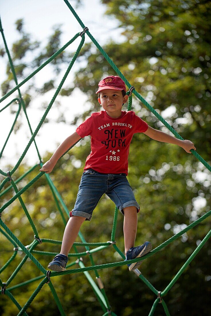 Kleiner Junge klettert auf einem Spinnennetz