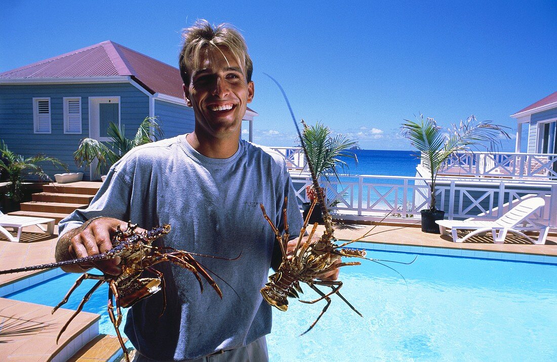 Man Holding Two Langouste Outside of a Resort