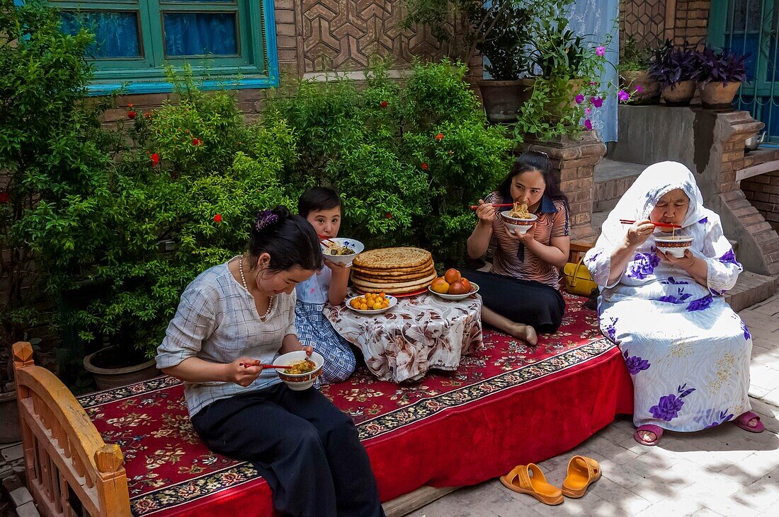 China, Xinjiang autonomous region, Kashgar, Uighur family enjoying a laghman, a dish made of home made noddles, mutton meat and vegetables