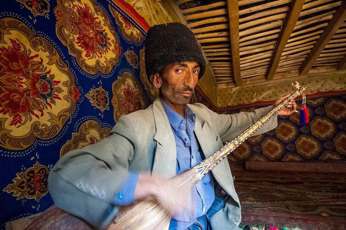 China, Xinjiang autonomous region, Sanju, shepherd with astrakan hat playing the dôtar, or traditional luth