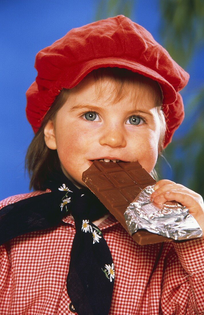 Kleines Mädchen beisst von einer Schokoladentafel ab