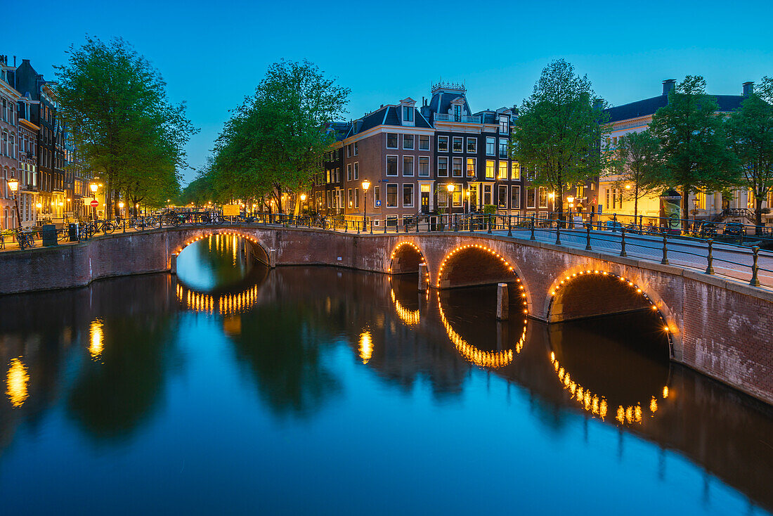 Illuminated bridge over Keizersgracht canal at twilight, Amsterdam, The Netherlands, Europe