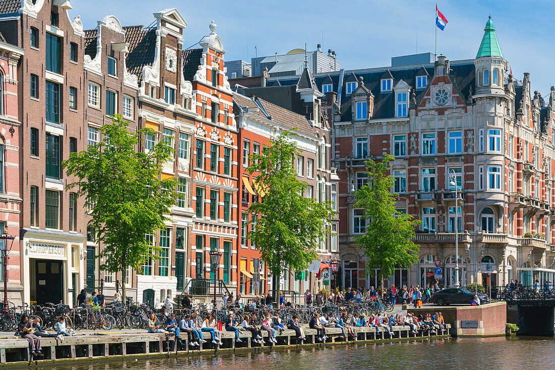 Students sitting by Rokin canal, Amsterdam, The Netherlands, Europe