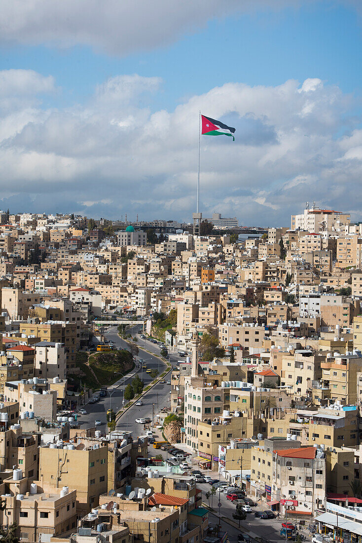 Nordöstlicher Bezirk mit der jordanischen Flagge an einem 126 m hohen Fahnenmast vor dem Raghadan-Palast im Hintergrund,von der Spitze des Zitadellenhügels aus gesehen,Amman,Jordanien,Naher Osten