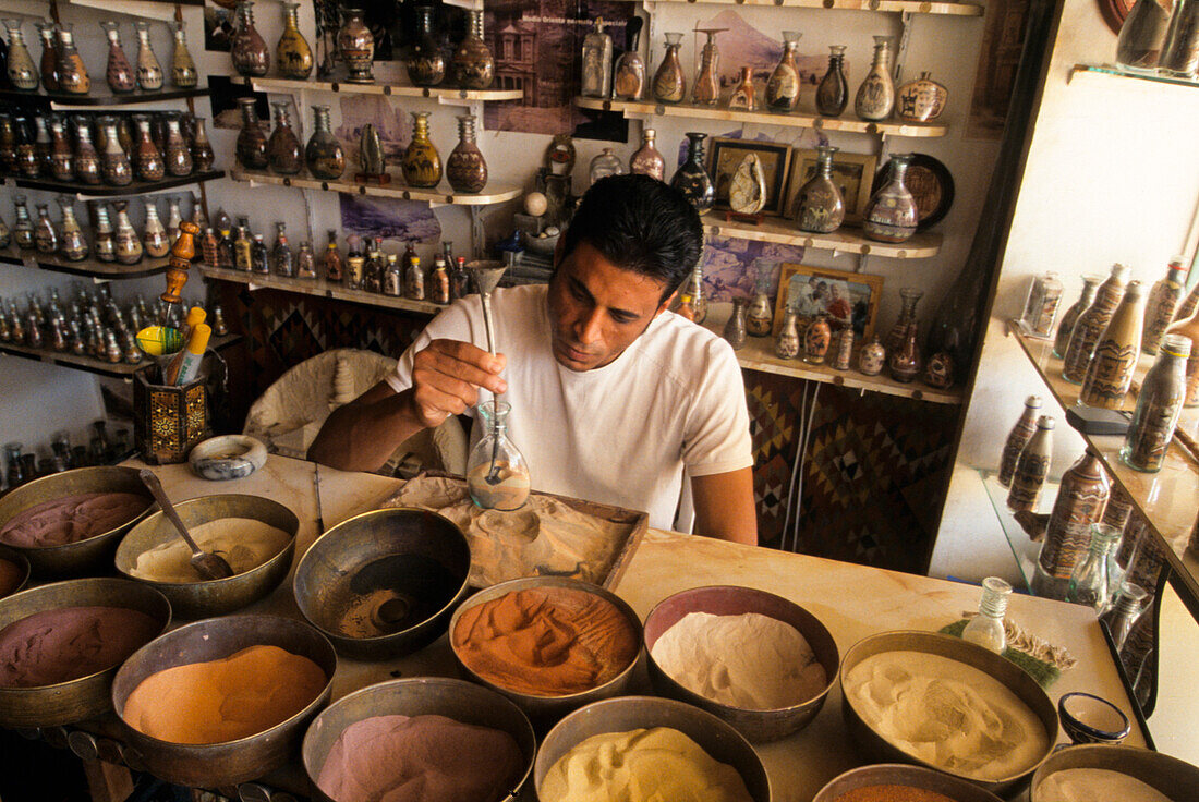 Ma working with colored sands used for making decorative bottles, Jordan, Middle East