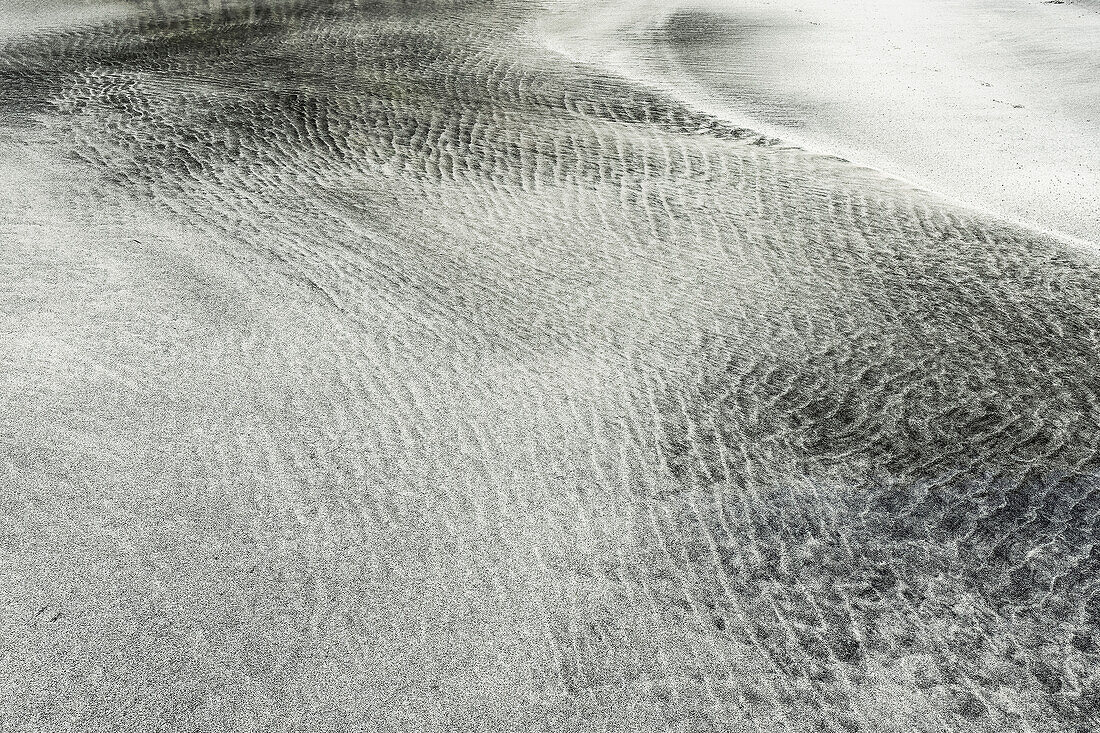 Tidal sorting of white sand and darker minerals into patterns at the west coast Talisker Bay beach, known as a white and black sand beach, an SSSI for its Tertiary basalt lava geology, Talisker Bay, Carbost, Skye, Inner Hebrides, Scotland, United Kingdom, Europe