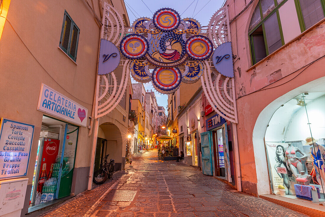 Blick auf Geschäfte in der Via Vittorio Emanuele im Fischereihafen in der Abenddämmerung,Procida,Phlegräische Inseln,Golf von Neapel,Kampanien,Süditalien,Italien,Europa