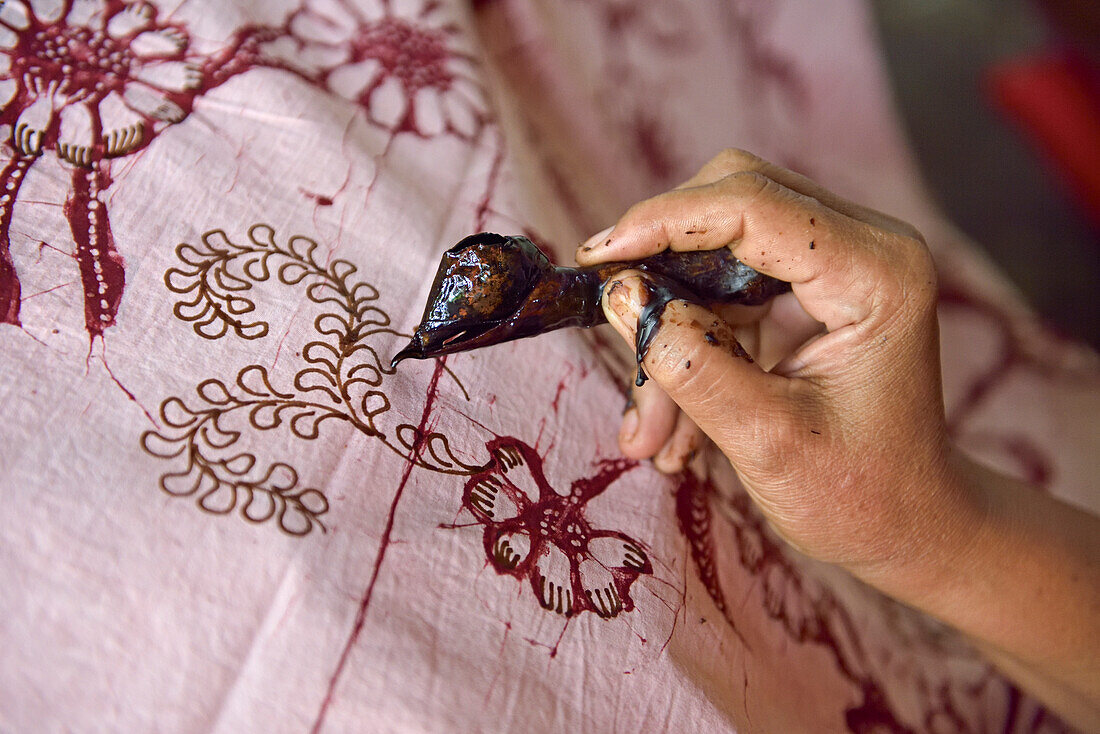 Woman using a pen-like tool (canting) to apply liquid hot wax to create pattern on the fabric before dyeing, workshop of Kidang Mas Batik House, Lasem, Java island, Indonesia, Southeast Asia, Asia