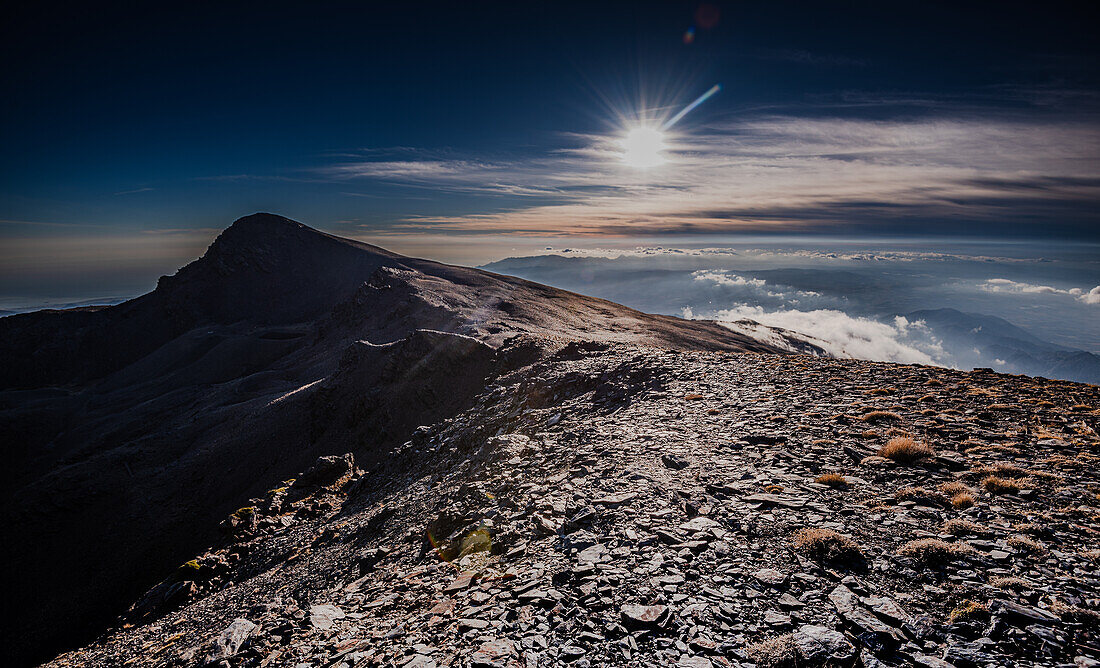 Dramatic rocky mountain ridge of the Sierra Nevada, with Cerro del Caballo against the sun, Andalusia, Spain, Europe