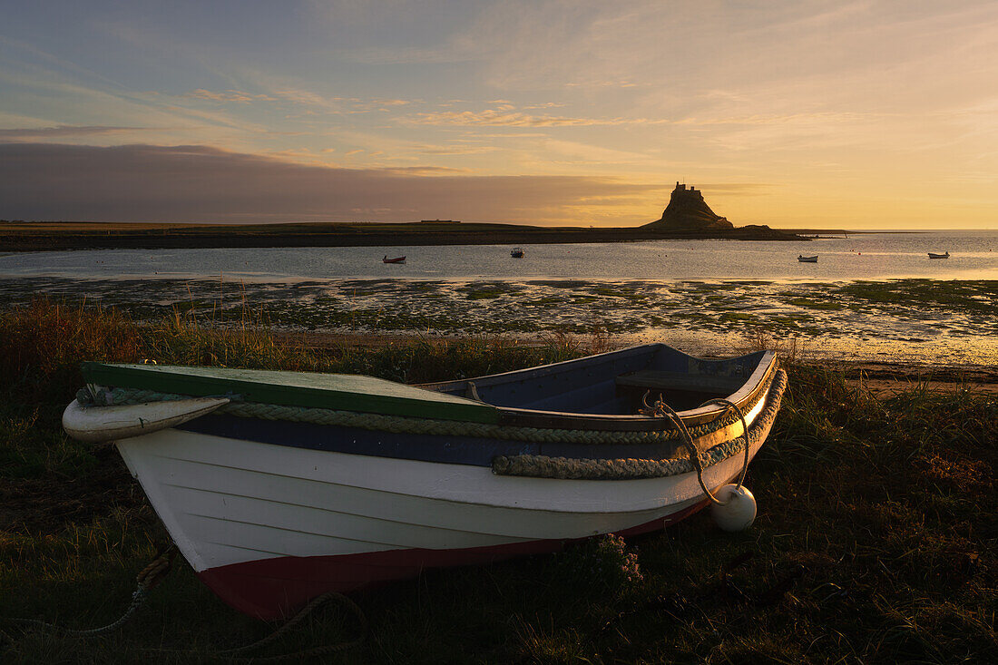 Boat on the shore of Holy Island with Lindisfarne Castle in the background, Northumberland, England, United Kingdom, Europe