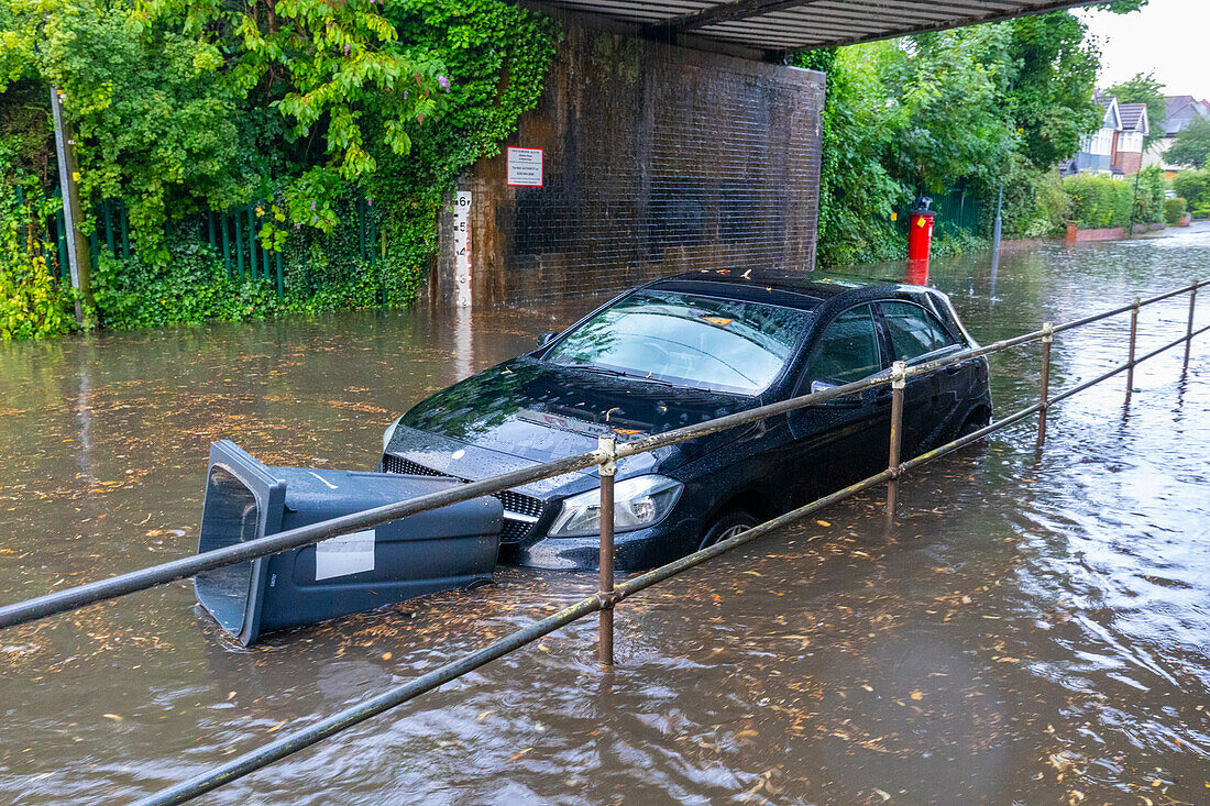 Flooded street with floating bin stuck in front of car, Sutton Coldfield, England, United Kingdom, Europe