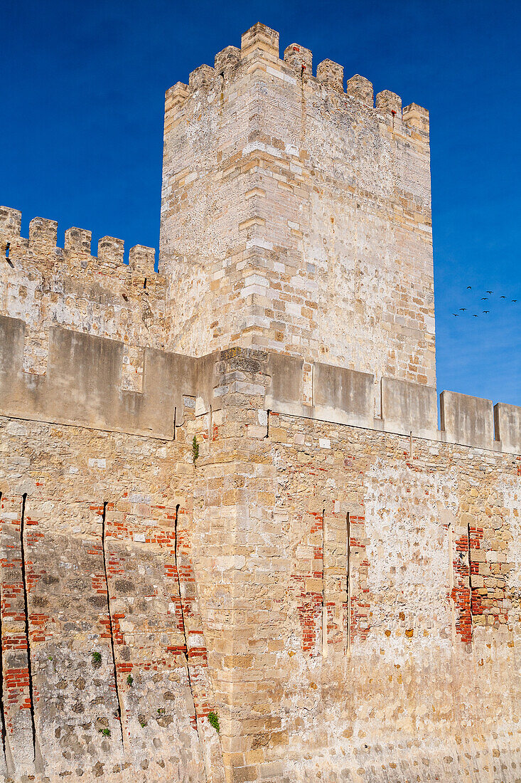 Saint George Castle stands proudly in Lisbon, showcasing its impressive fortified walls and stunning architecture under a clear blue sky.