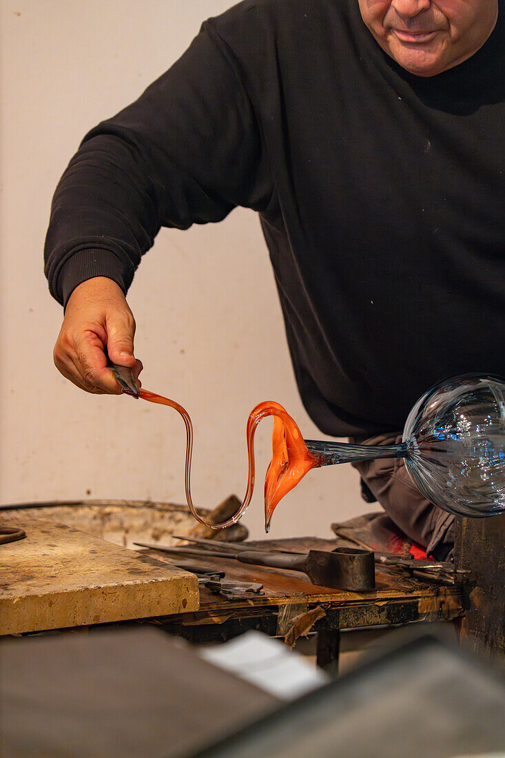 Der Glasbläser spannt das Glas mit Hebeböcken,um einen Henkel zu formen,bei einer Glasbläservorführung in Venedig,Italien.