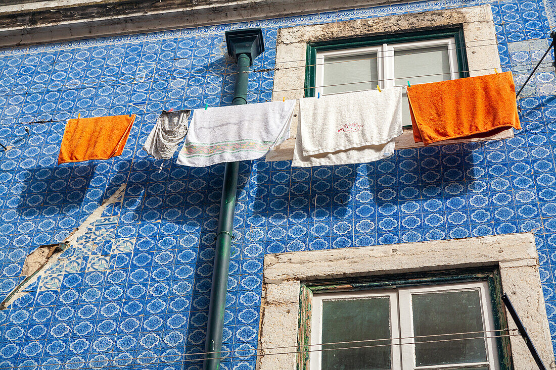 Colorful laundry hangs between windows of a traditional tiled building in Bairro Alto, showcasing Lisbon's charming urban life.