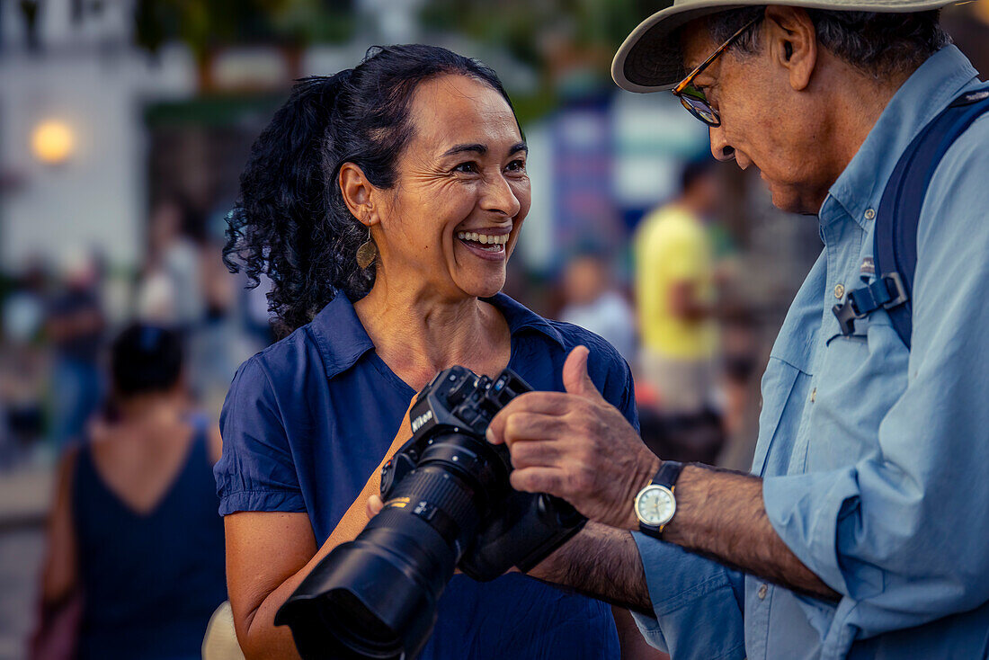 An American photographer shows his photos to a friendly local woman the Plaza El Libertador in Jardin, Colombia