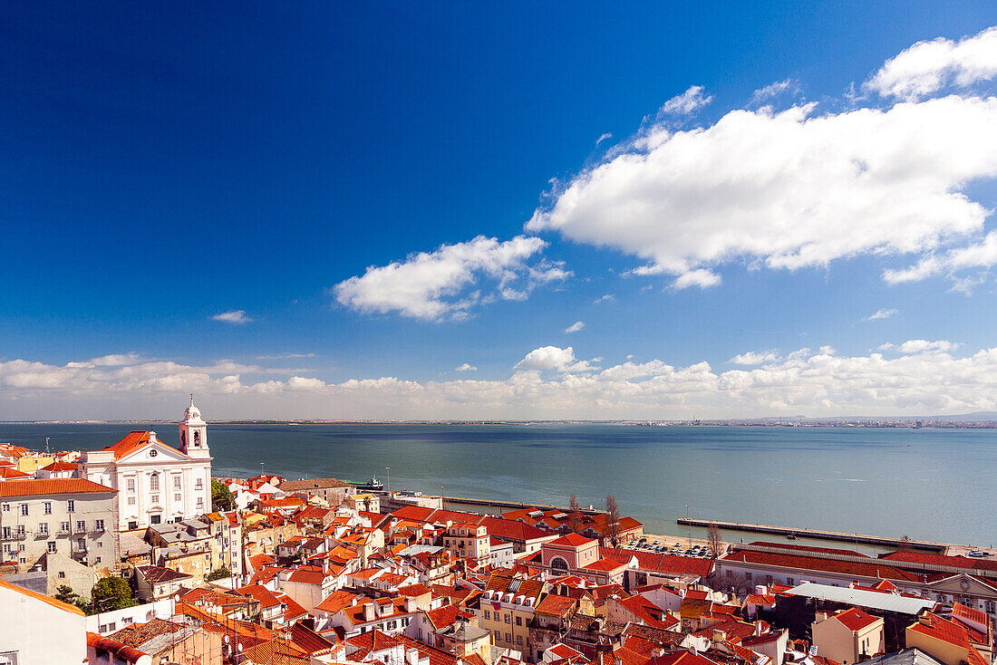 Stunning landscape of the Tejo estuary and Santo Estevao Church in Lisbon, Portugal, under a bright blue sky. The combination of water and architecture creates a tranquil and picturesque scene.