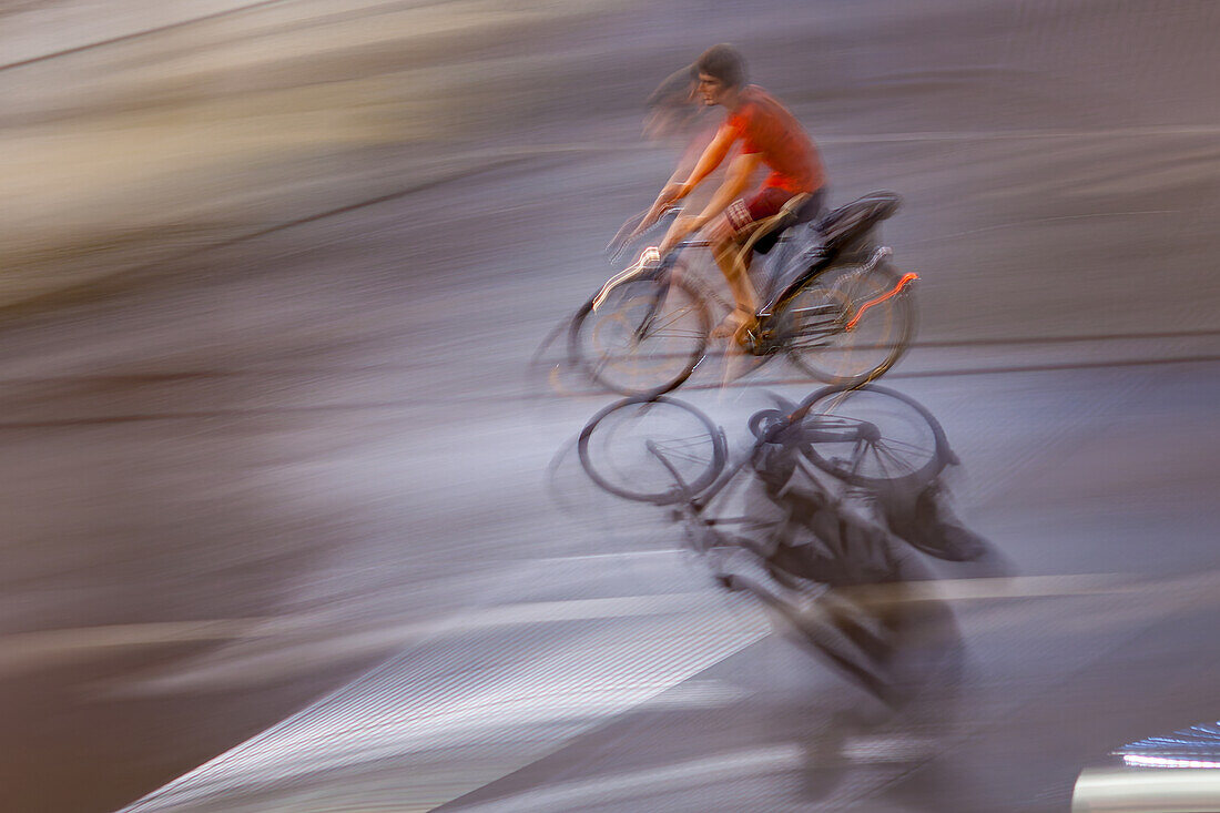 Dynamic panning shot capturing a cyclist moving swiftly through the city streets at night, illustrating motion and urban life.