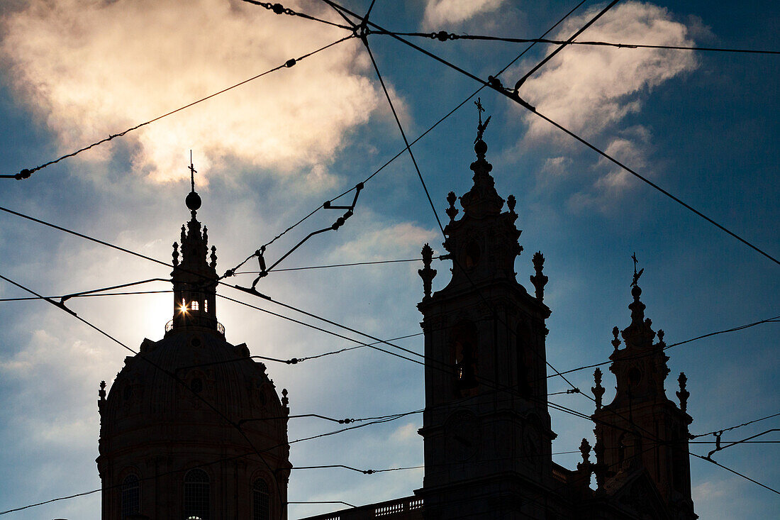 The Basilica da Estrela stands majestically against the sky, its twin towers silhouetted by the clouds and urban landscape of Lisbon.