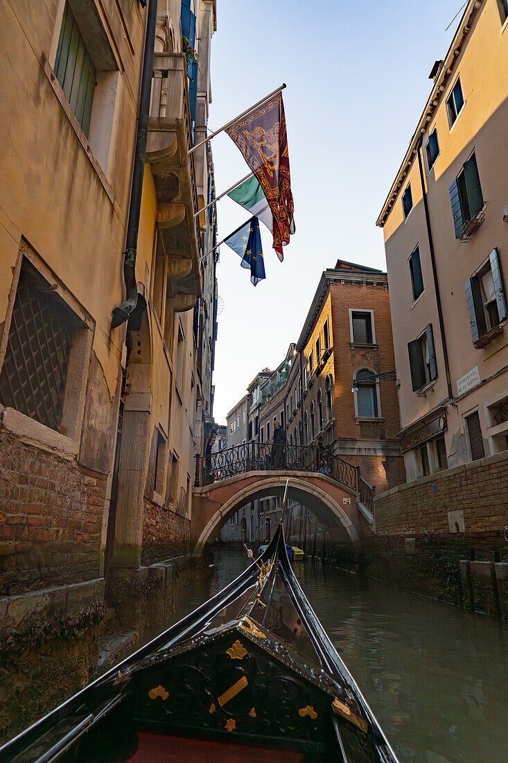 A gondola approaches a stone bridge over a canal in Venice, Italy.