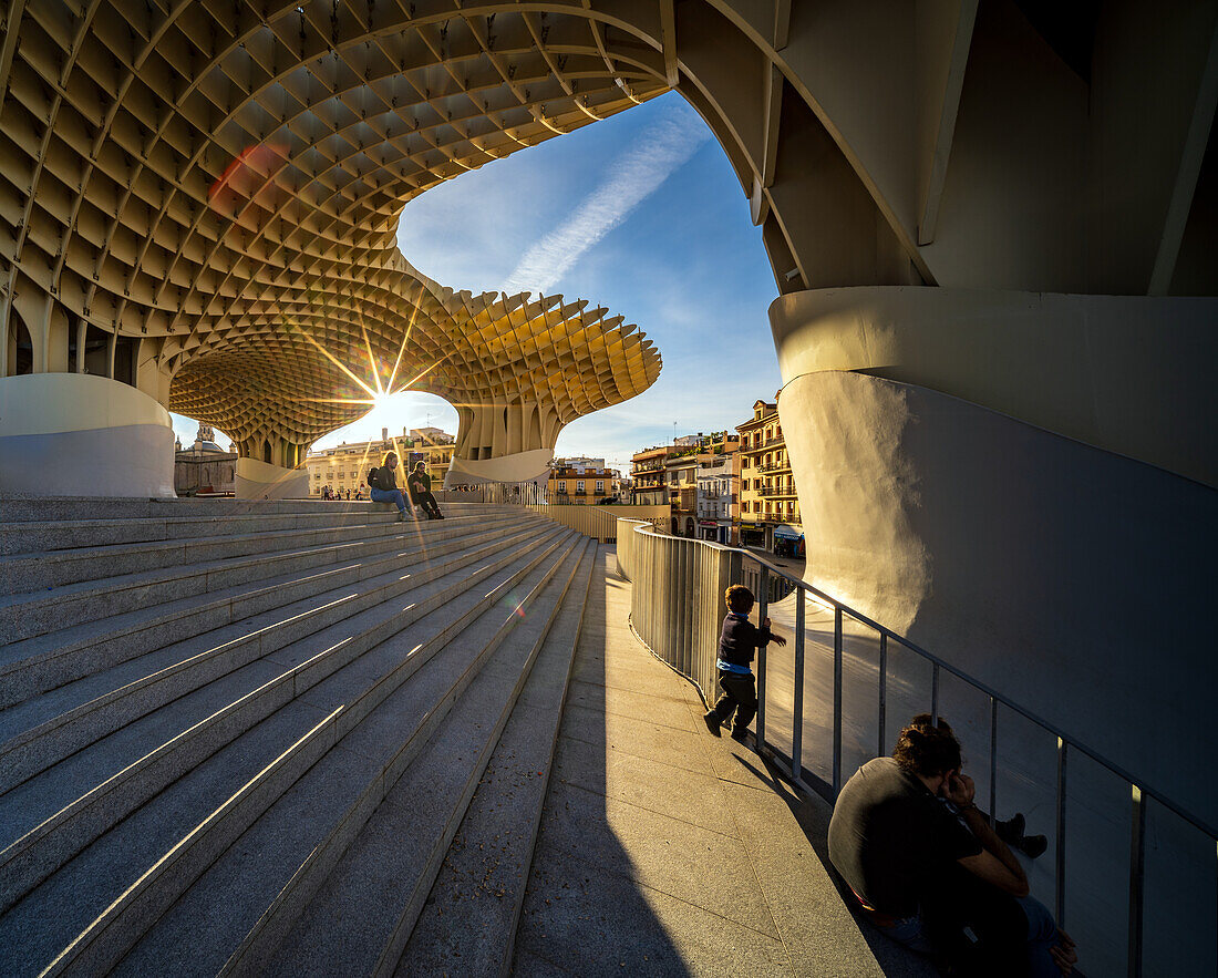 Ein fesselnder Blick auf Las Setas in Sevilla bei Sonnenuntergang,der die moderne Architektur und das dynamische Stadtleben unterstreicht. Das warme Licht hebt die geometrischen Muster hervor und schafft eine heitere Atmosphäre.