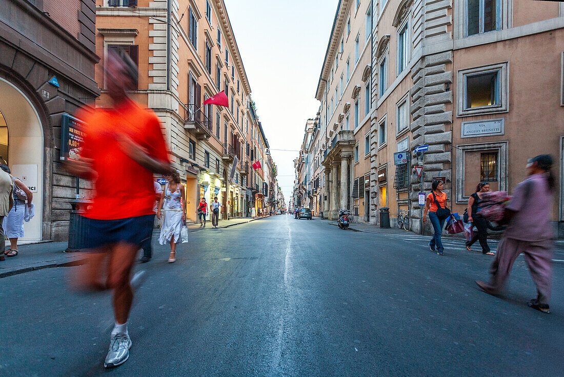 Rome, Italy, July 22 2017, People walk along Via del Corso while a jogger speeds past in Rome, capturing the lively atmosphere of the city.