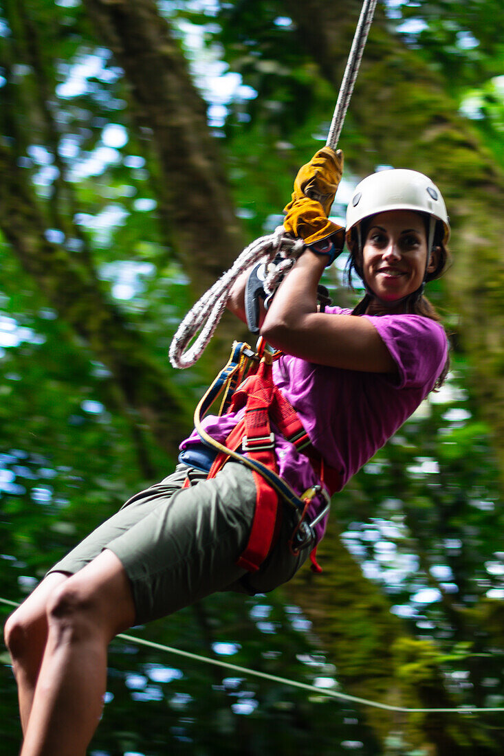 Young caucasian woman having fun during a Canopy tour in Costa Rica