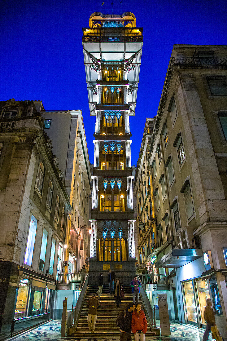 Lisbon, Portugal, March 1 2007, The Santa Justa Elevator stands tall in Baixa, Lisbon, glowing beautifully at night while people stroll nearby.