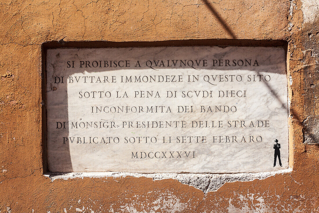 A stone plaque in Rome warns against littering on the street, highlighting historical waste disposal regulations.