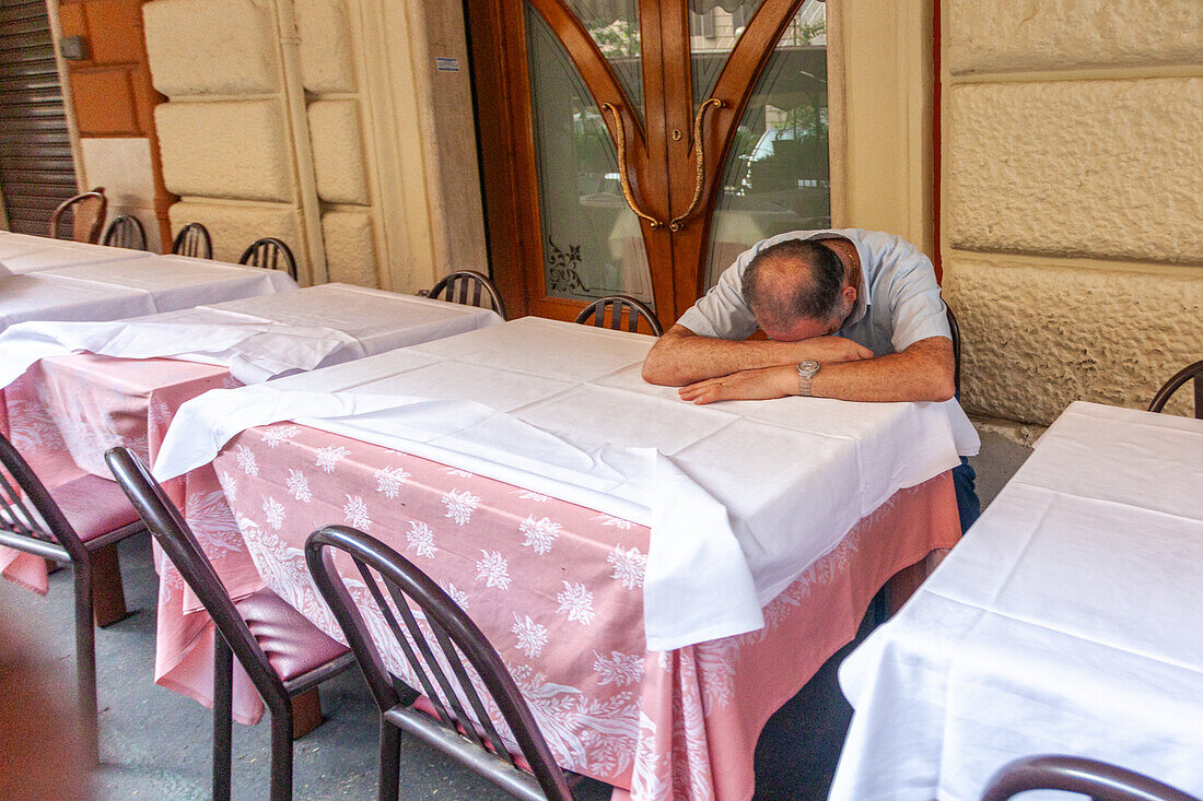 Ein Kellner macht eine Pause auf der Terrasse eines Restaurants in Rom.