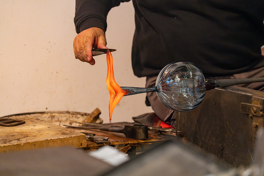 Bei einer Glasbläservorführung in Venedig,Italien,spannt der Glasbläser das Glas mit Hebeln,um einen Henkel zu formen.