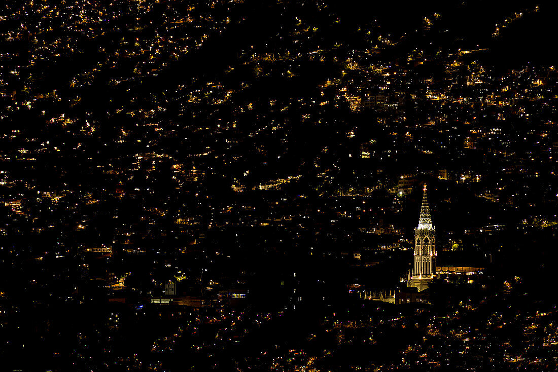 A church stands out among the city lights in one of the many poorer mountain barrios of Medellin, Colombia