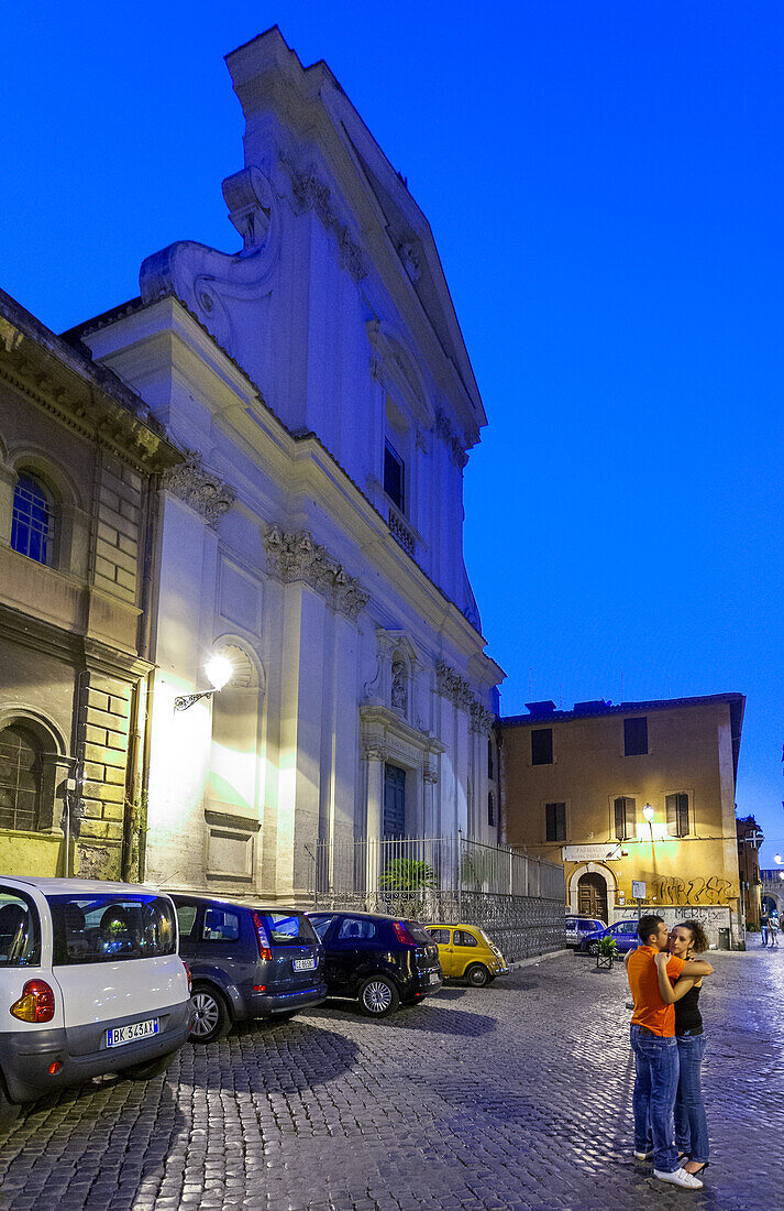 Rom,Italien,22. Juli 2017,In Trastevere,Rom,umarmt sich ein Paar auf einer Kopfsteinpflasterstraße unter dem Nachthimmel,umgeben von charmanter Architektur und geparkten Autos.