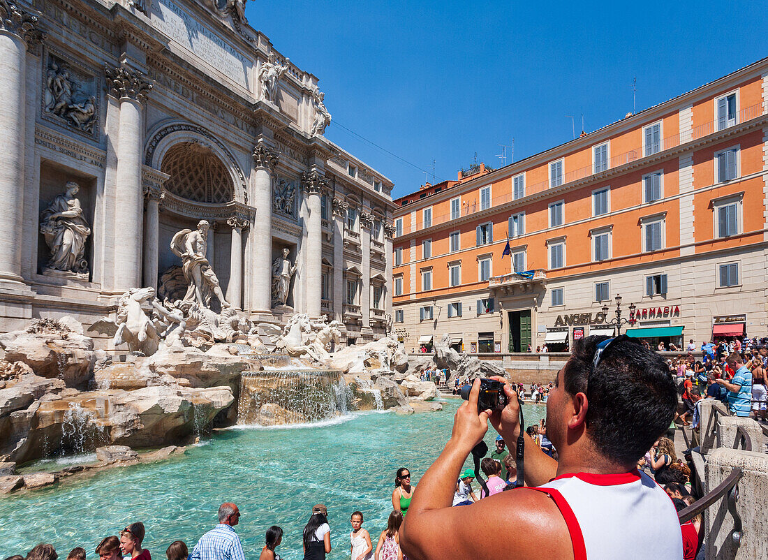 Rome, Italy, July 22 2017, Tourists enthusiastically take pictures of the stunning Trevi Fountain in Rome, enjoying the vibrant atmosphere under a clear blue sky.