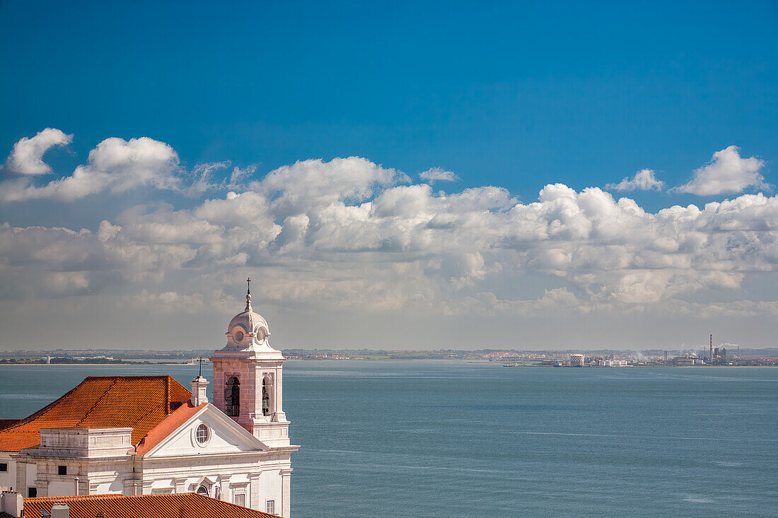 Atemberaubende Landschaft an der Tejo-Mündung und die Kirche Santo Estevao in Lissabon,Portugal,unter strahlend blauem Himmel. Die Kombination aus Wasser und Architektur schafft ein ruhiges und malerisches Bild.