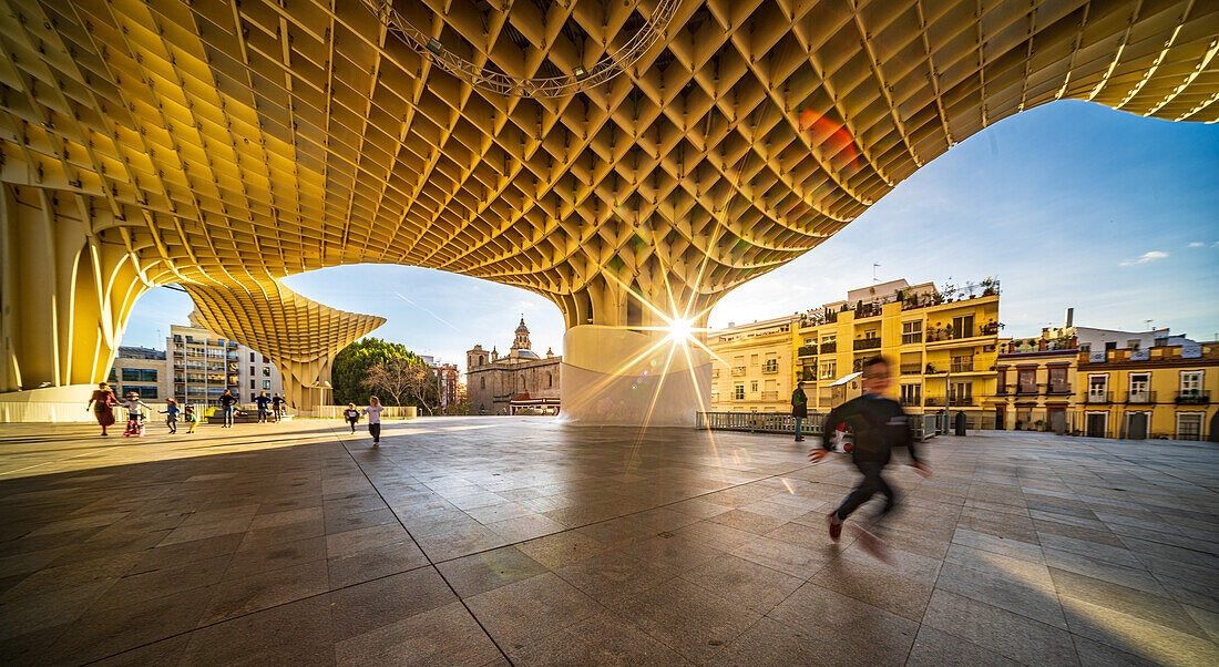 Sevilla,Spanien,28. Januar 2021,Blick auf das Gebäude Las Setas in Sevilla,Spanien,mit spazierenden Menschen und der untergehenden Sonne im Hintergrund. Die moderne Architektur bildet einen auffälligen Kontrast zu den traditionellen Gebäuden.