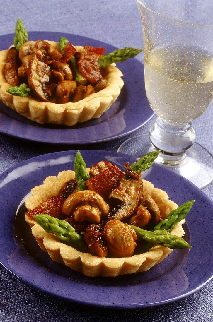 Two ham and mushrooms tartlets with green asparagus