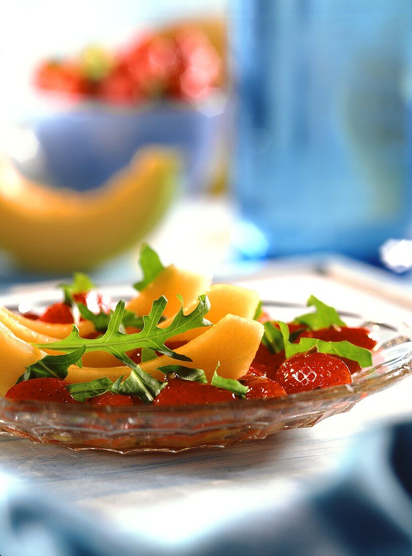 Melone mit pikantem Erdbeersalat und Rucolablättern