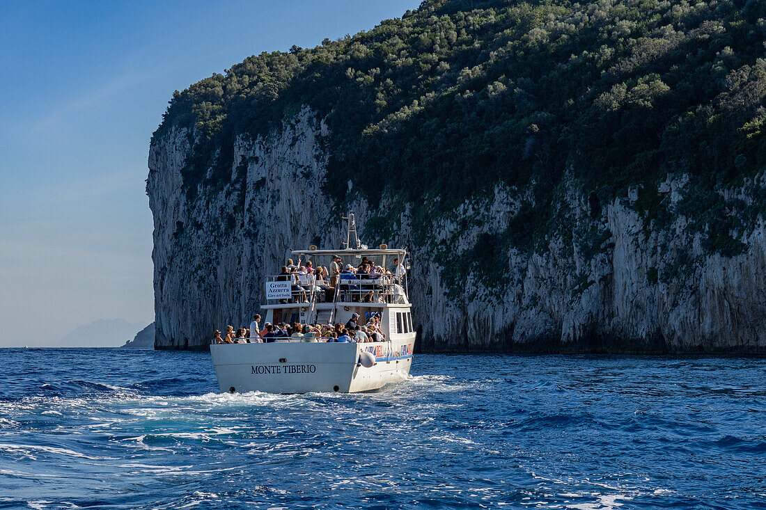 A tour boat full of passengers circumnavigating the island of Capri, Italy.