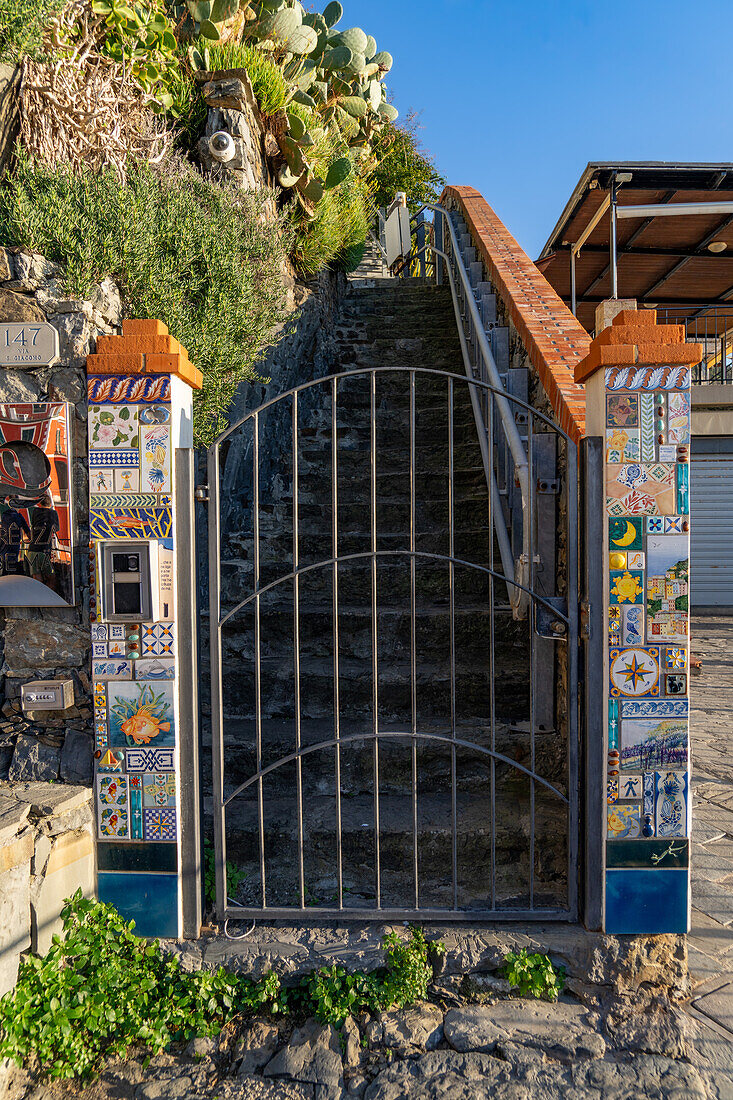 Ein Tor zu einem Wohnhaus mit bunten Keramikfliesen in Riomaggiore, Cinque Terre, Italien.