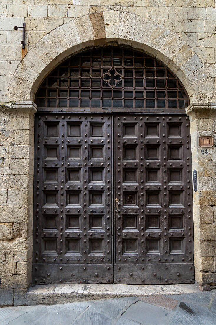 The heavy studded wooden doors of the Chancellery Palace in the medieval city of San Gimignano, Italy.